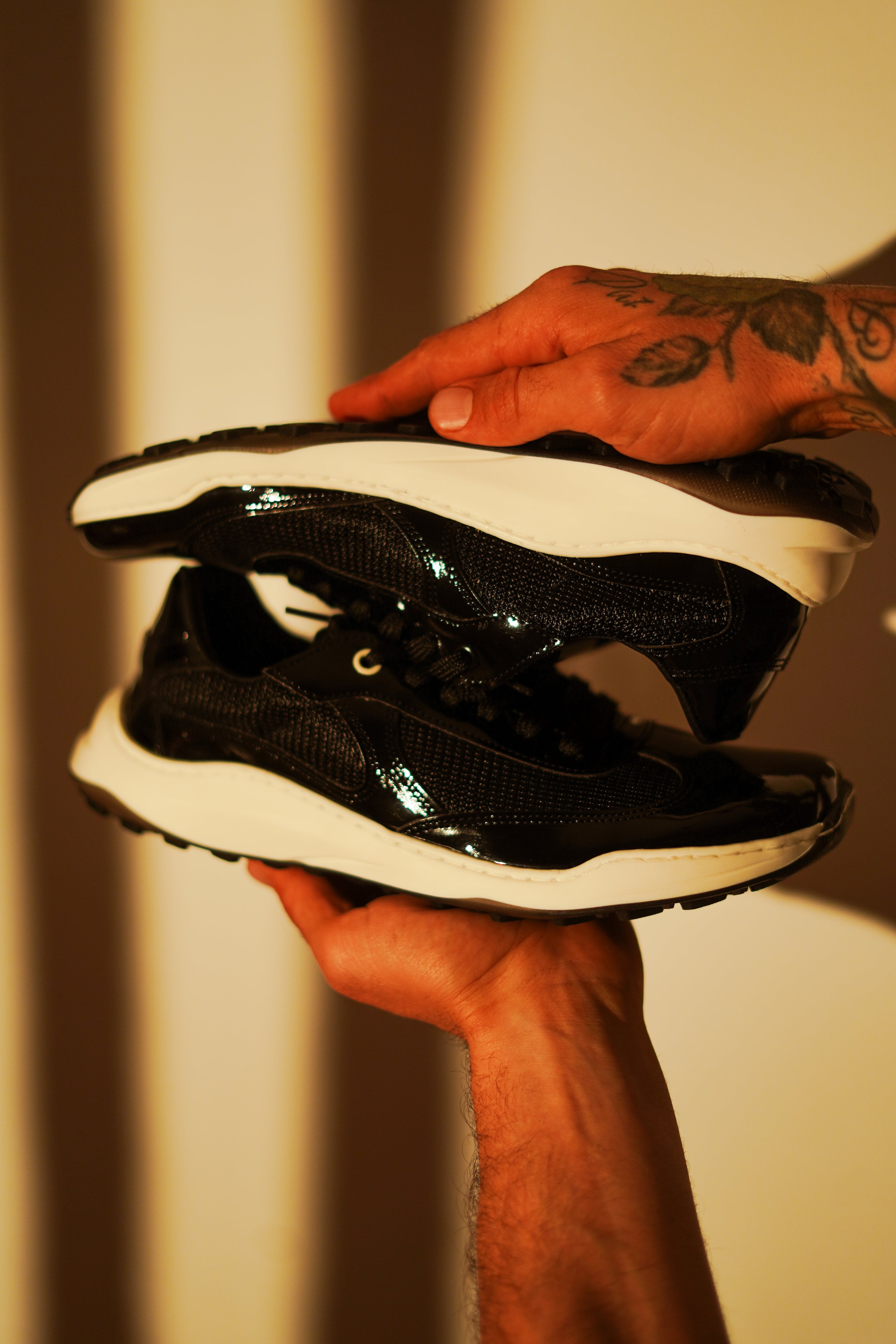 Zapatos barefoot negros VR Origen de VoaRoots sobre estructura metálica con fondo gris minimalista. Calzado natural, urbano y sostenible.